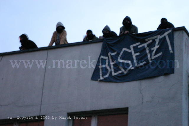 Hausbesetzer mit Transparent "Besetzt"