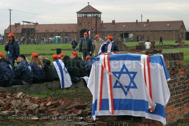 Israel-Fahne auf Ruine eines Kamins einer Gefangenenbaracke, im Hintergrund das Einfahrtstor
