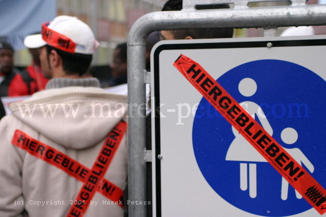 Schriftzug "Hiergeblieben" auf Demonstrant und auf Verkehrszeichen