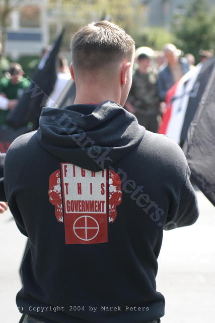 Neonazi mit Kapuzenpullover "Fight this government" mit Totenköpfen und Fadenkreuz