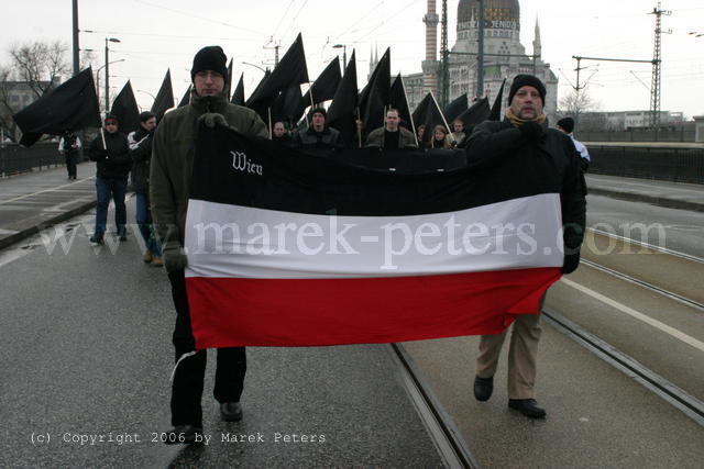 Österreichische Neonazis mit schwarz-weiss-roter Fahne "Wien" vor schwarzen Fahnen